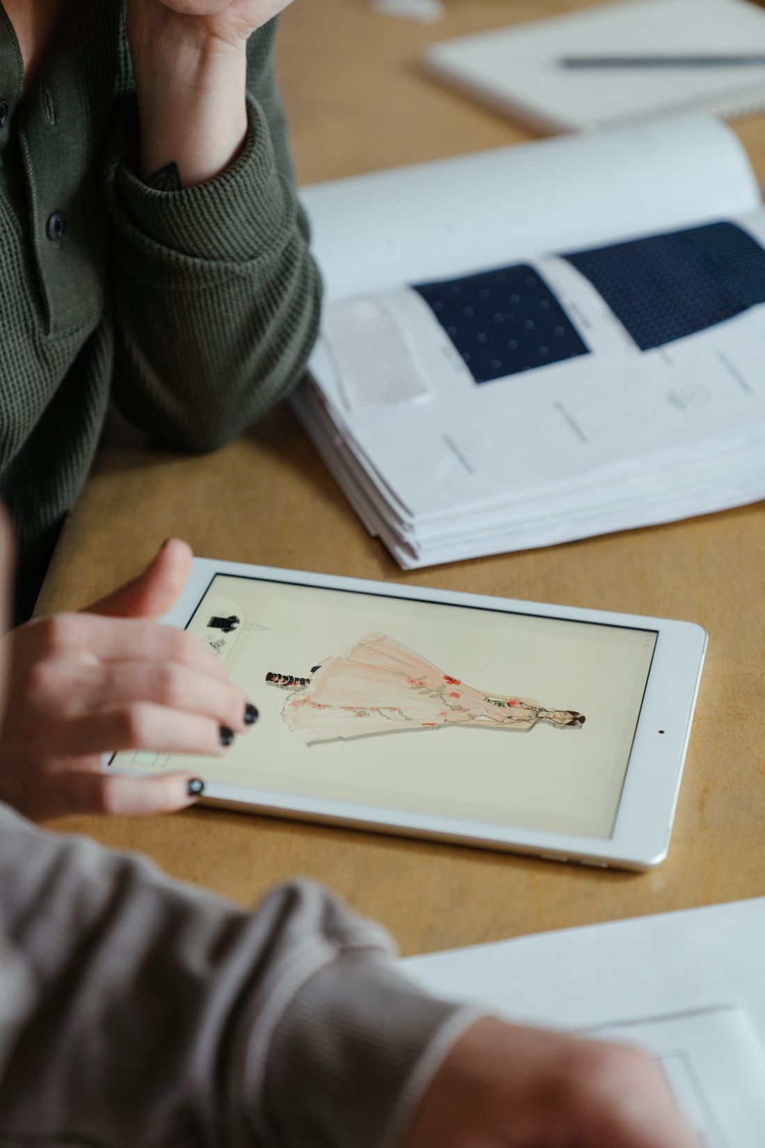 A fashion designer drawing clothing ideas on a tablet.