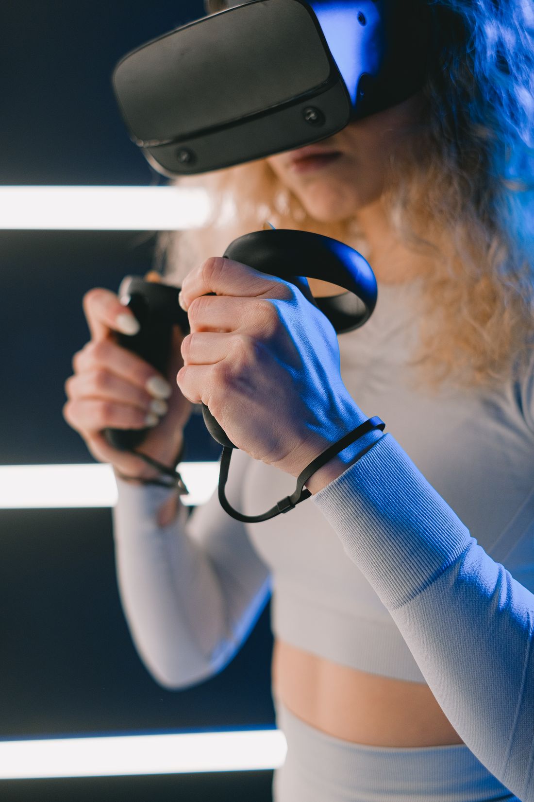 A woman using a virtual reality headset and controllers indoors.